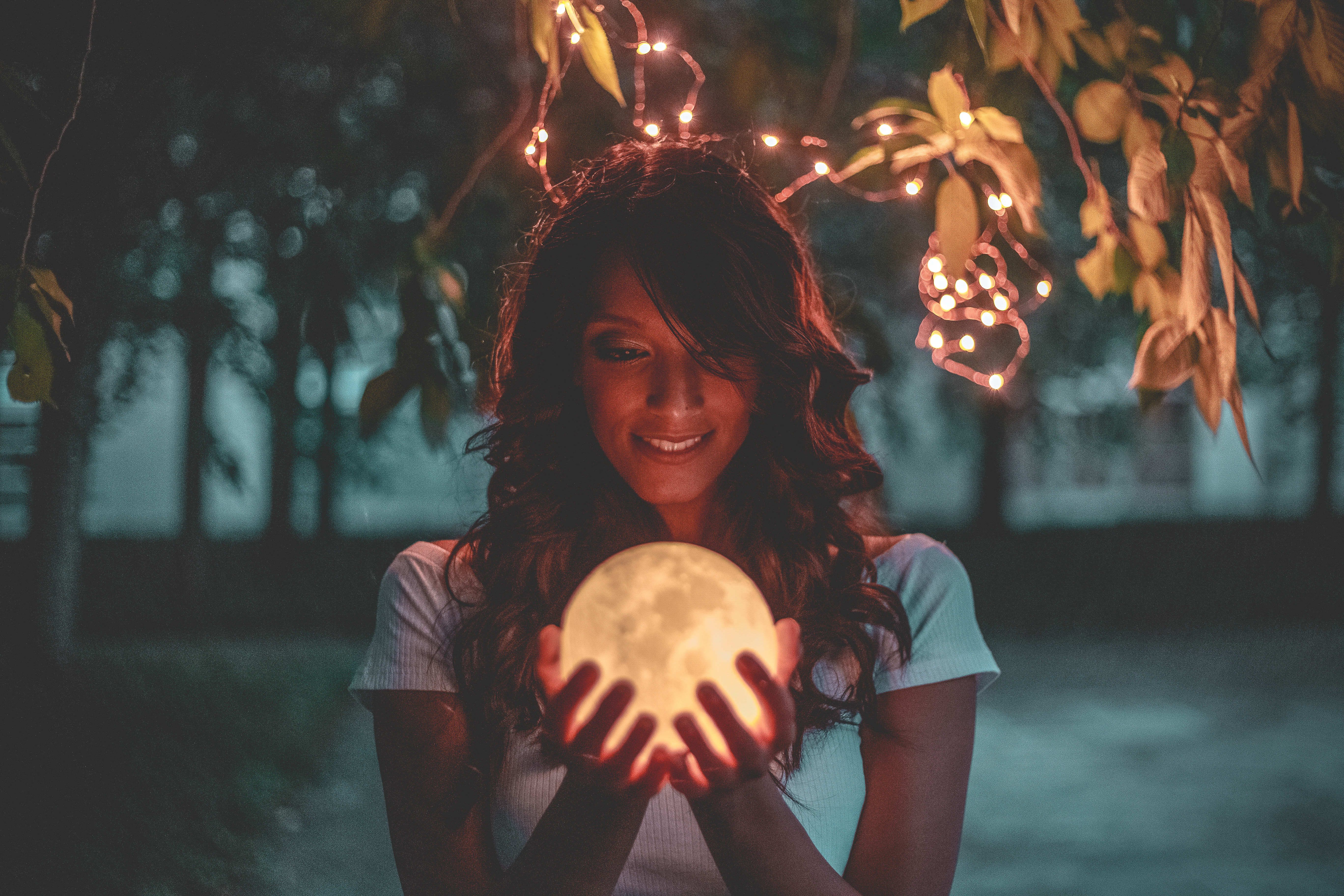 Portrait of smiling young woman holding illuminated moon